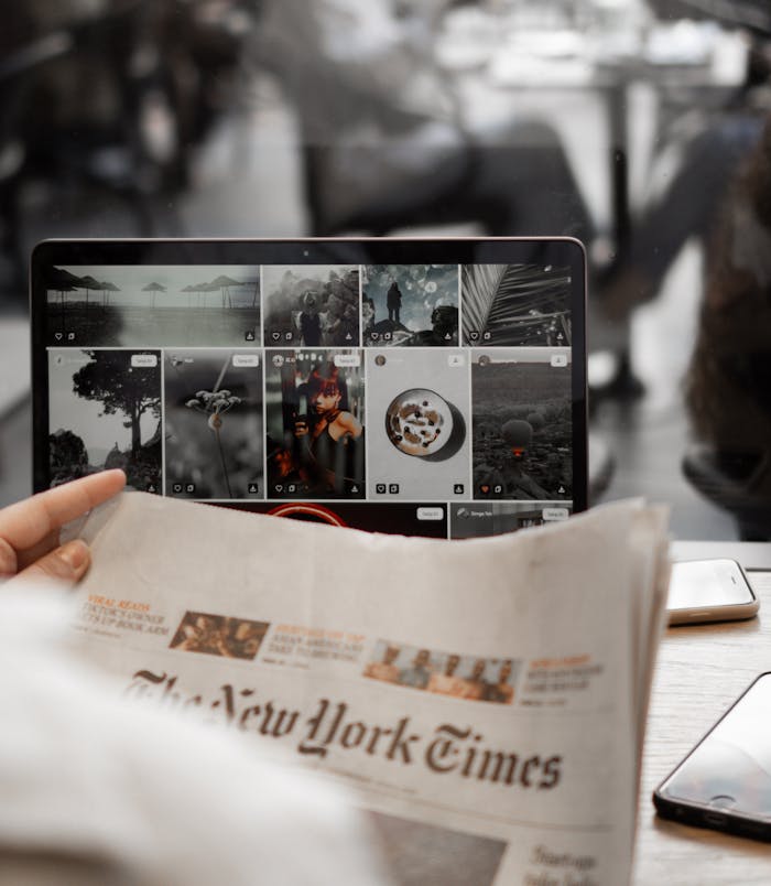 about-01 A person reading a newspaper while browsing images on a laptop, symbolizing remote work lifestyle.
