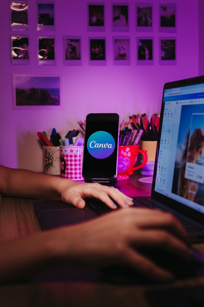 services-02 A creative home workspace with a laptop and smartphone displaying Canva, showcasing a vibrant, organized desk setup.