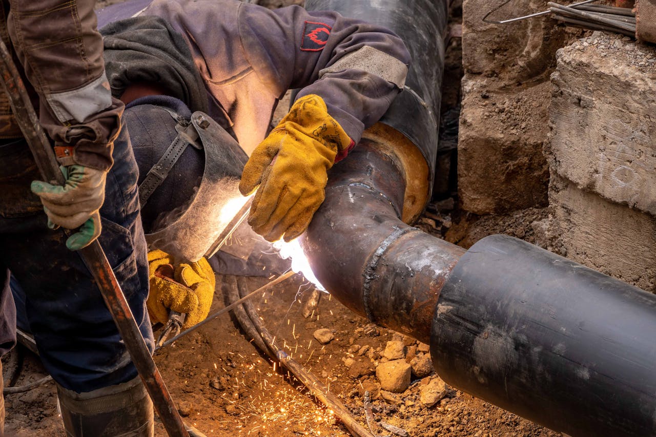 The Art of Drawing Readers In: Your attractive post title goes here Close-up of a skilled worker welding steel pipes in an industrial setting, showcasing expertise and safety gear.