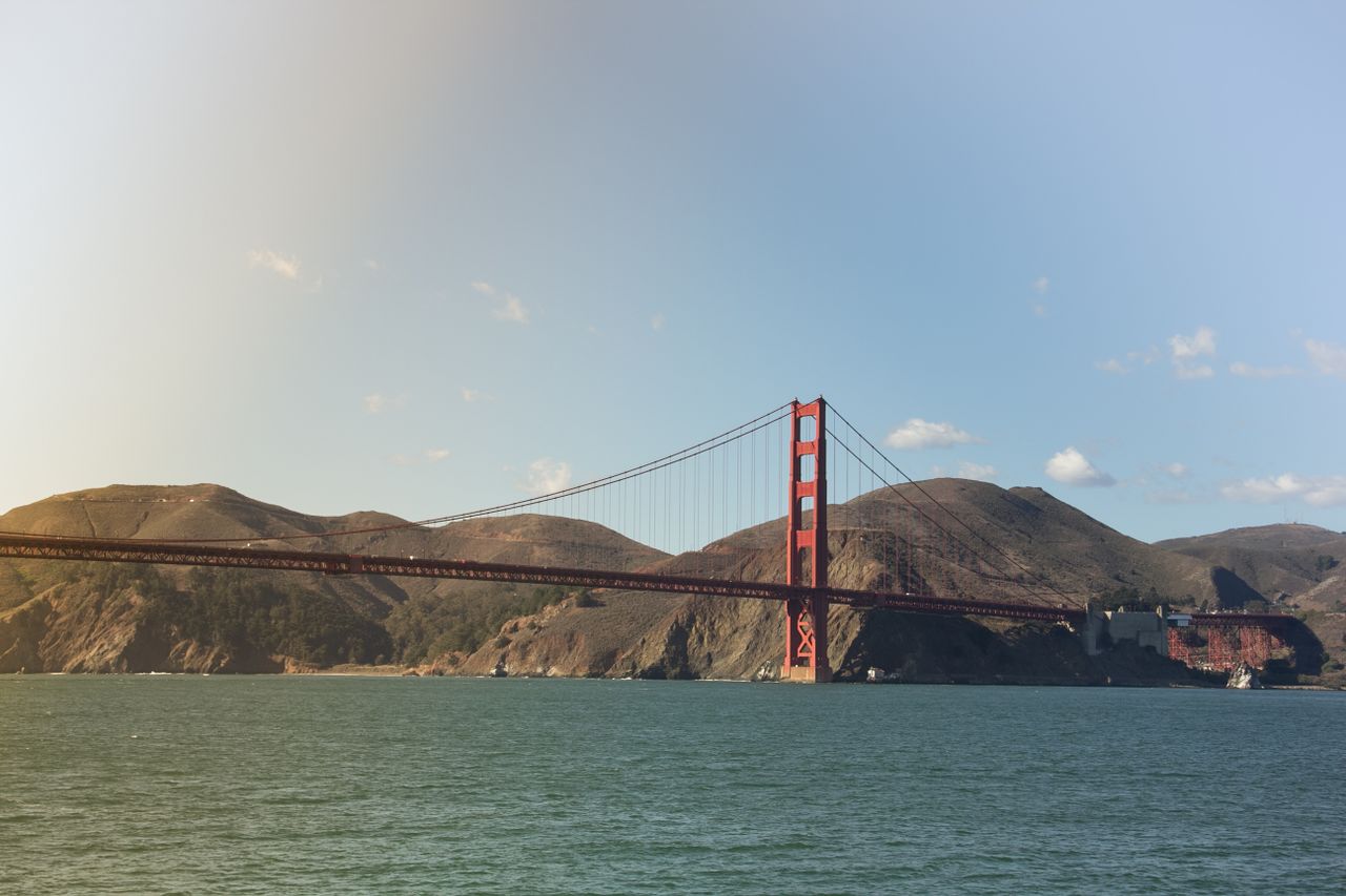 Scenic view of the iconic Golden Gate Bridge spanning the ocean with hills in the background.